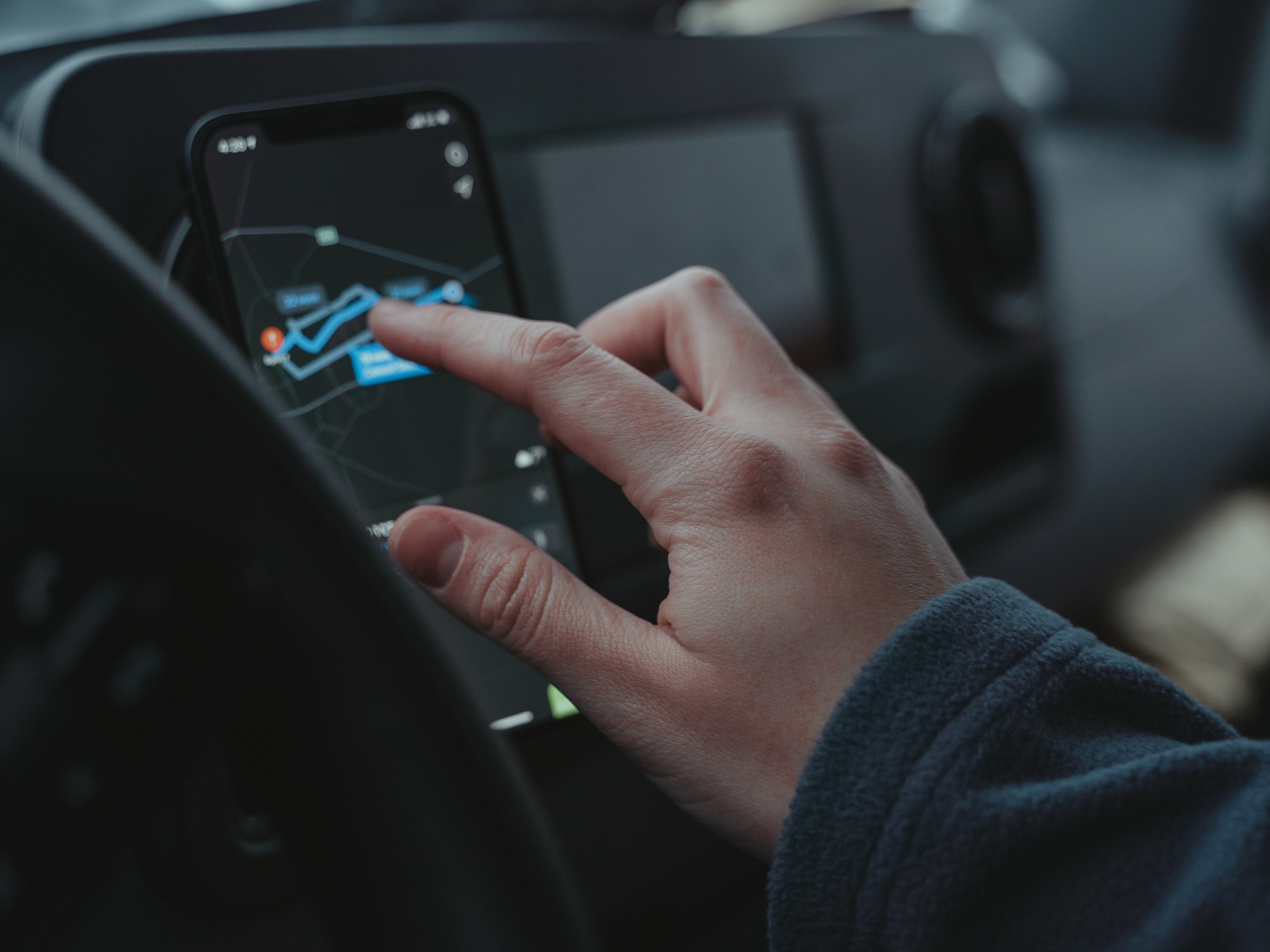 Hand, die Ortungssystem mit Smartfon im Auto bedient Hand, die Ortungssystem mit Smartfon im Auto bedient
